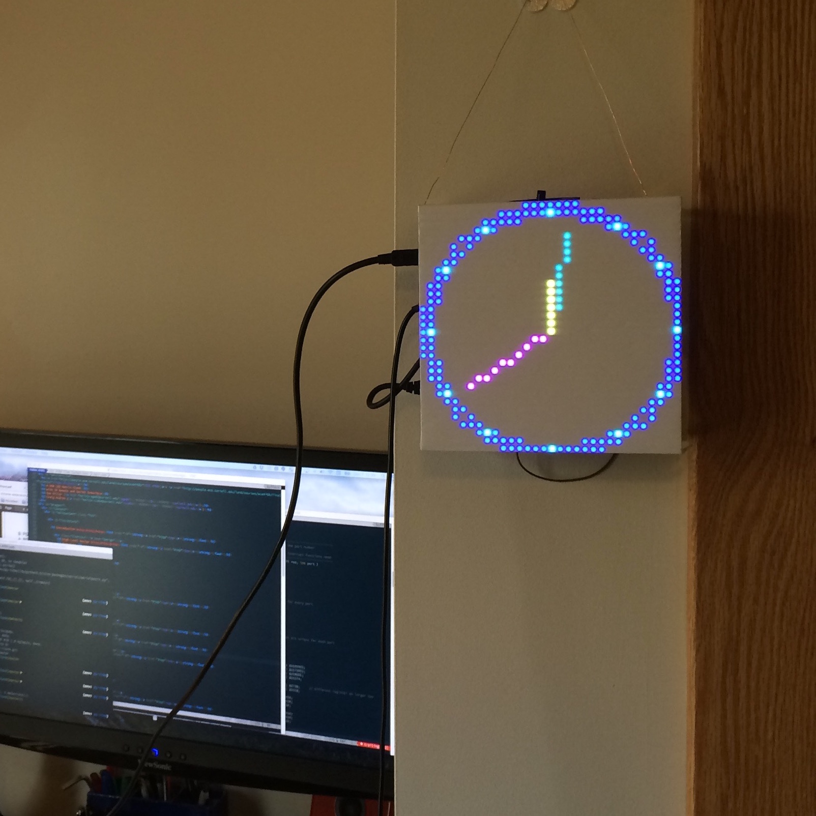 RGB LED Matrix hanging on wall showing analog clock display.